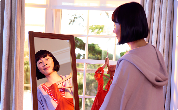 Lady smiling at her reflection in the mirror with dress in hand